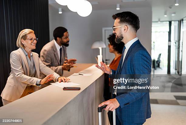 hombre de negocios que se registra en la recepción del hotel con equipaje - turismo responsable fotografías e imágenes de stock