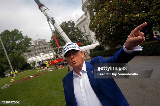 President Donald Trump talks to reporters as workers install a new flag pole on the South Lawn of the White House on June 18, 2025 in Washington, DC....