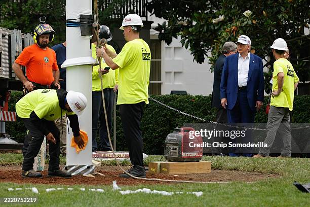 President Donald Trump talks with workers as they install a new flag pole on the South Lawn of the White House on June 18, 2025 in Washington, DC....