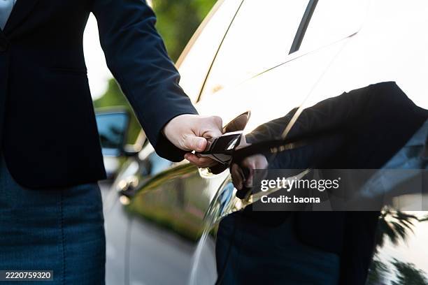 well dressed woman opening a car door - luxeauto stockfoto's en -beelden
