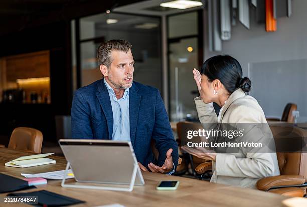 businesswoman arguing with her male colleague during a meeting - annoying colleague stock pictures, royalty-free photos & images