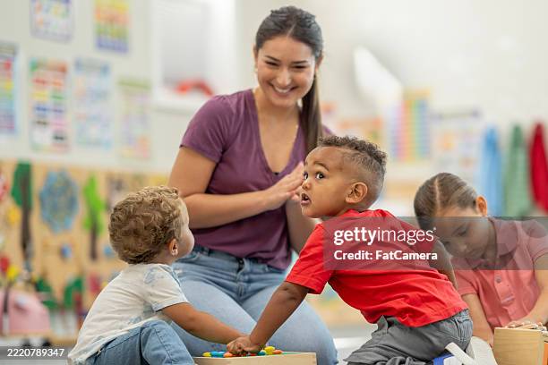 teacher interacting with diverse preschool kids during classroom activities - showing empathy stock pictures, royalty-free photos & images