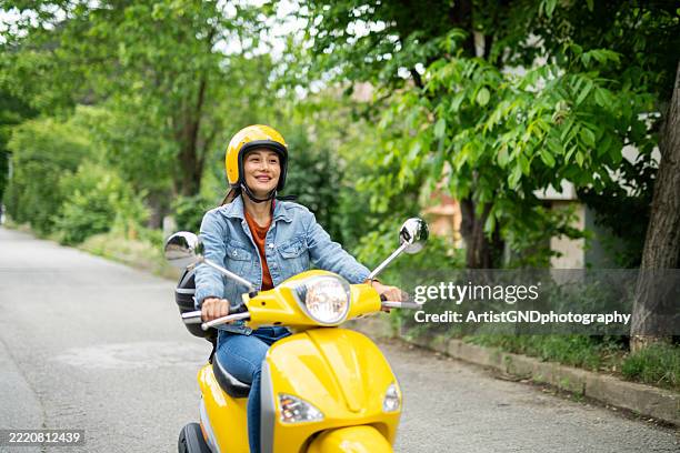 happy asian woman riding her scooter in the town. - lambreta imagens e fotografias de stock