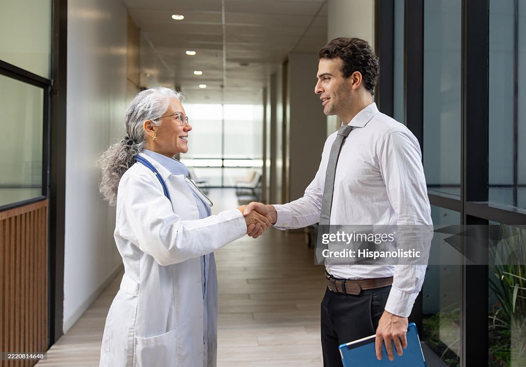 Médico feliz estrechando la mano de un agente de seguros de salud en el hospital