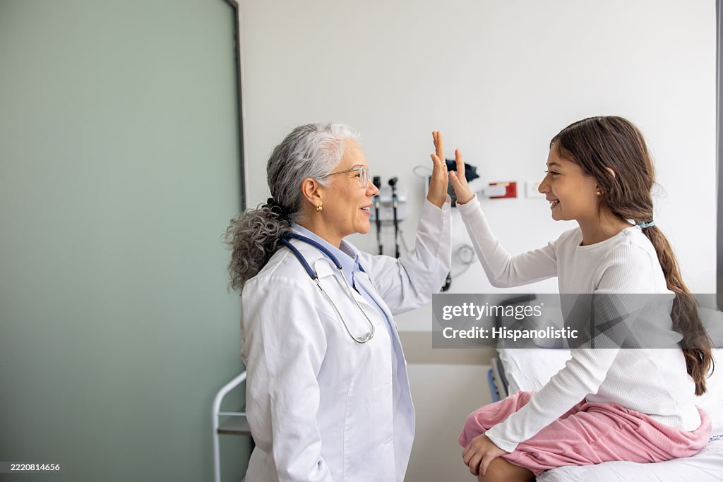 Glücklicher Arzt, der einem Mädchen im Krankenhaus ein High-Five gibt