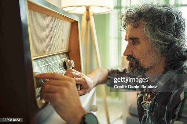 retro tech comeback. man tuning vintage radio at home - radio broadcasting stock pictures, royalty-free photos & images