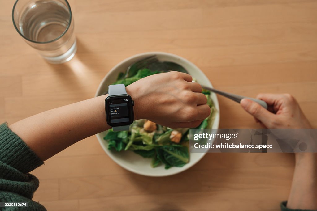 Mulher asiática usando relógio inteligente para rastrear seus níveis de glicose, adotando a conveniência da tecnologia vestível para monitoramento de saúde em tempo real