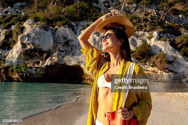young woman enjoying summer vacation on a sunny beach - sombrero de sol fotografías e imágenes de stock