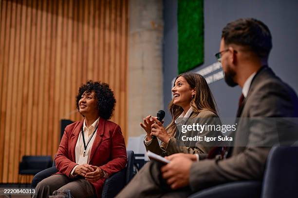 businesswomen speaking at a conference using a microphone - panel stage stock pictures, royalty-free photos & images