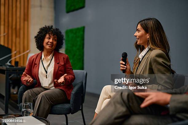 businesswomen speaking at a conference using a microphone - panel discussion stock pictures, royalty-free photos & images