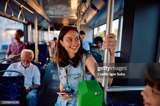 junge frau lächelt, während sie ihr telefon im bus benutzt - bus stock-fotos und bilder
