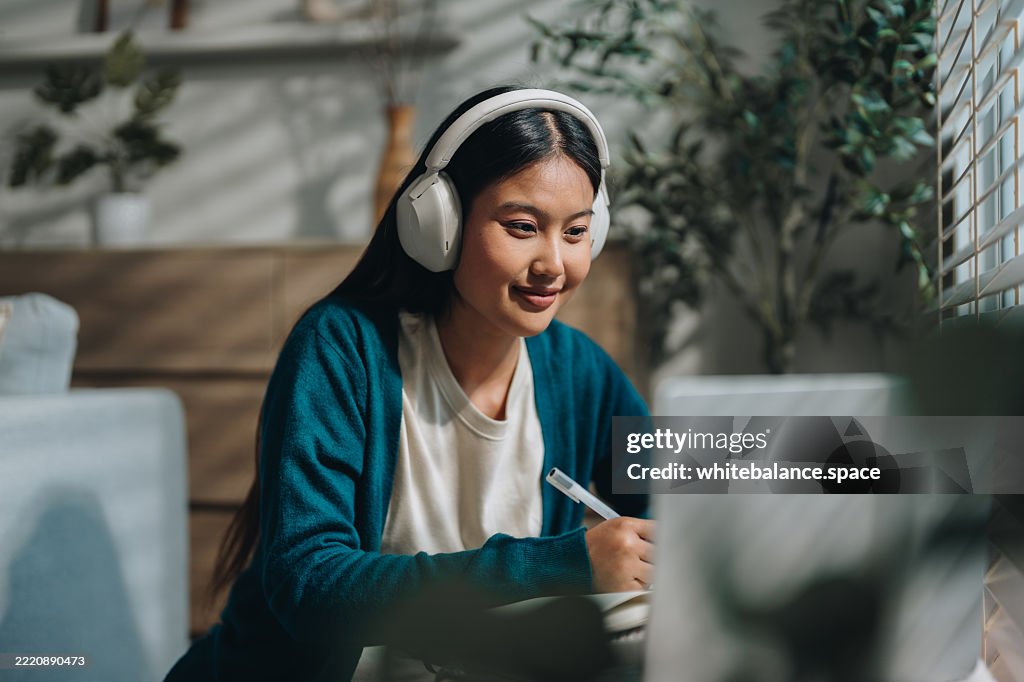 Mulher desfrutando de sua aula online, tomando notas com atenção enquanto permanece engajada e focada