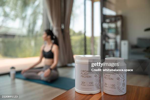 molkenproteinbehälter im vordergrund mit einer frau, die yoga praktiziert - molke stock-fotos und bilder