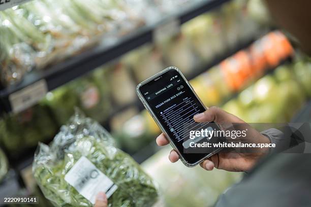 close-up shot of a man using his smartphone to check the ingredient list while selecting groceries from the shelf - buy online pick up in store stock pictures, royalty-free photos & images