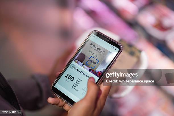 close-up shot of a man using his smartphone to check his smart fridge while grocery shopping at the supermarket - buy online pick up in store stock pictures, royalty-free photos & images