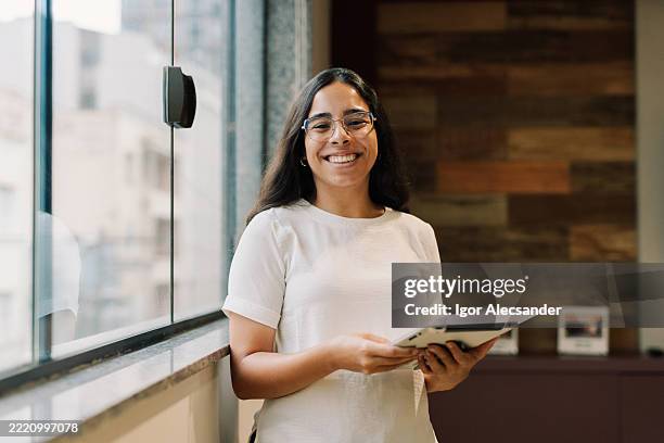 female intern standing confidently with digital device - praktikant bildbanksfoton och bilder