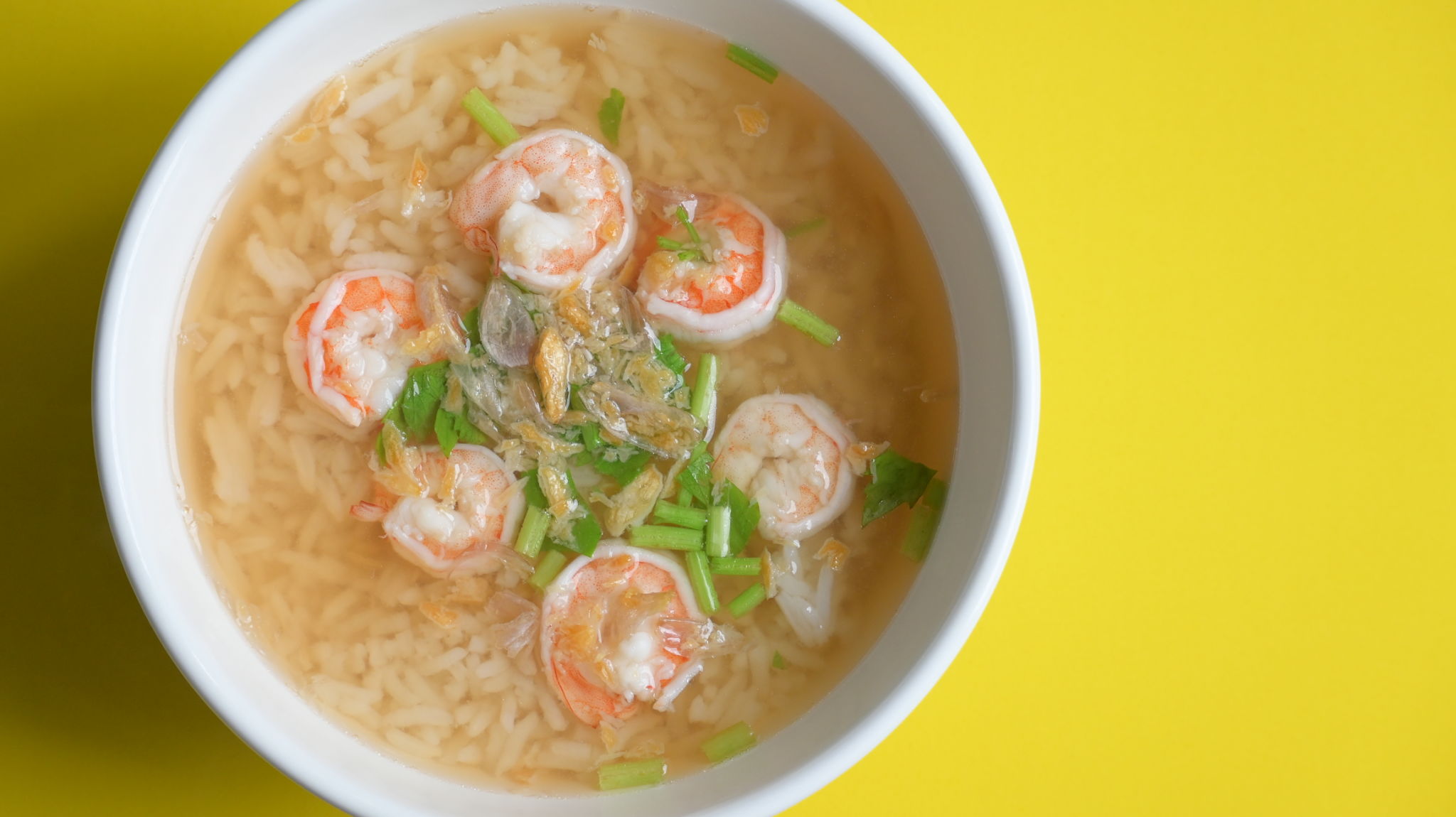 rice soup with shrimp in white bowl on yellow background rice soup with shrimp in white bowl on yellow background