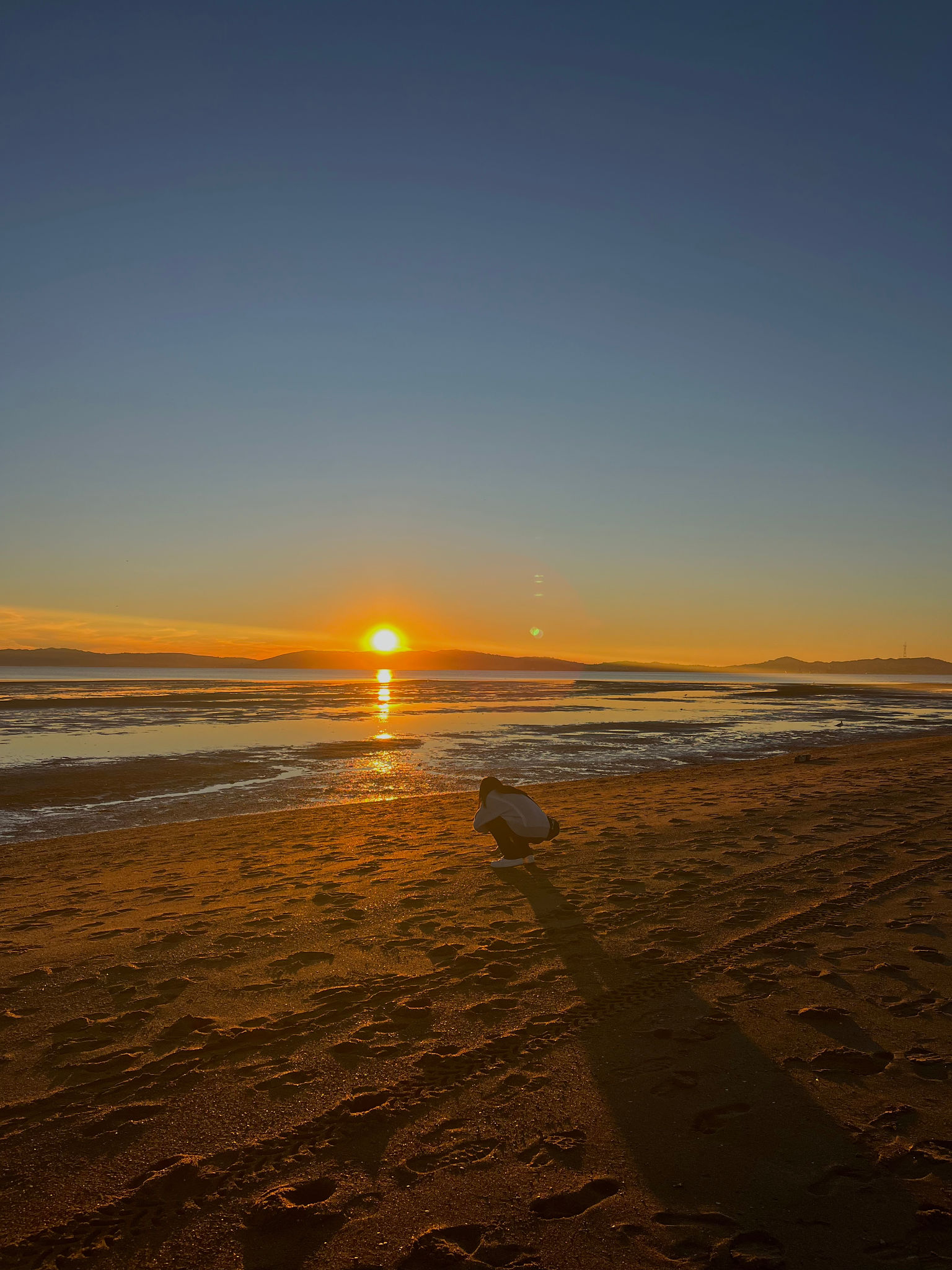Crouching Person Silhouetted on Beach Sunset Crouching Person Silhouetted on Beach Sunset
