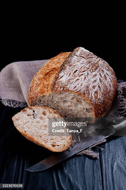pane a lievitazione naturale pagnotta e fetta con coltello su tavolo rustico in legno - lievito naturale foto e immagini stock
