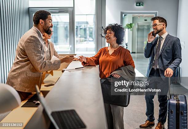 businesswoman checking in at hotel reception - travel check in stock pictures, royalty-free photos & images