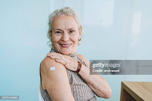 woman showing vaccinated arm - bandage stock pictures, royalty-free photos & images