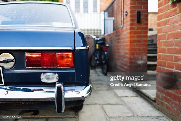 rear view of a classic blue car parked on a residential street - parachoques fotografías e imágenes de stock