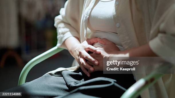 asian woman having stomachache - buik stockfoto's en -beelden
