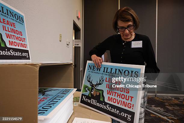 Paula Jablonski, of Cook County, grabs lawn signs about New Illinois from a box during the New Illinois Seventh Constitutional Convention on April 5...