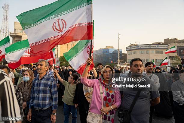 Demonstrators wave flags and cheer during a gathering to honor Iran’s military forces, following the announcement of a ceasefire between Israel and...