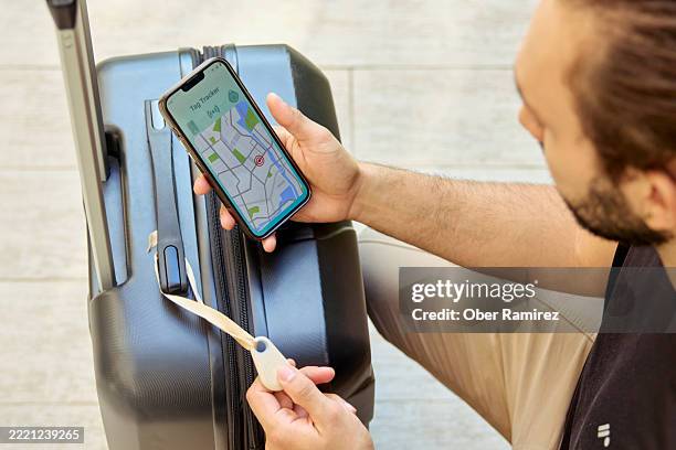 a man tests the smart tracker attached to his luggage on his mobile phone. - location tracking stock pictures, royalty-free photos & images