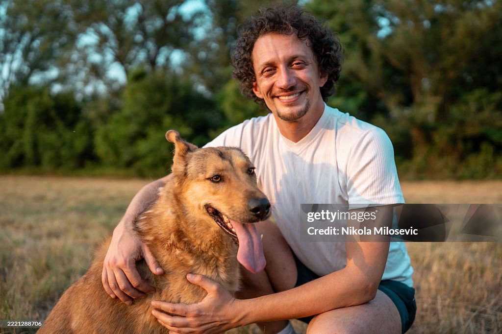 Smiling Man Enjoying the Outdoors with His Furry Companion on a Sunny Day