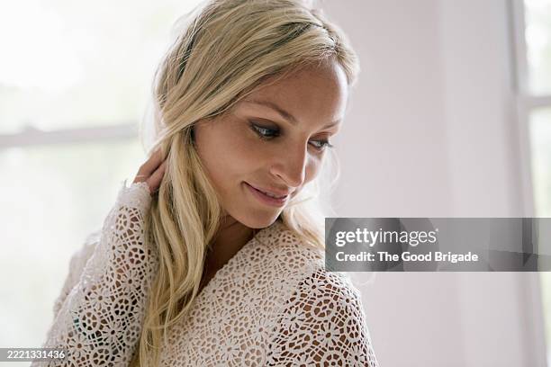 smiling female bride wearing laced bridal top looking down with hand in hair - lace dress stock pictures, royalty-free photos & images