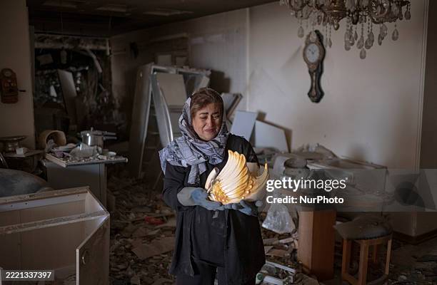 An Iranian woman mourns while holding a broken sculpture that is a memory from her father, as she stands in her apartment, which is destroyed in...
