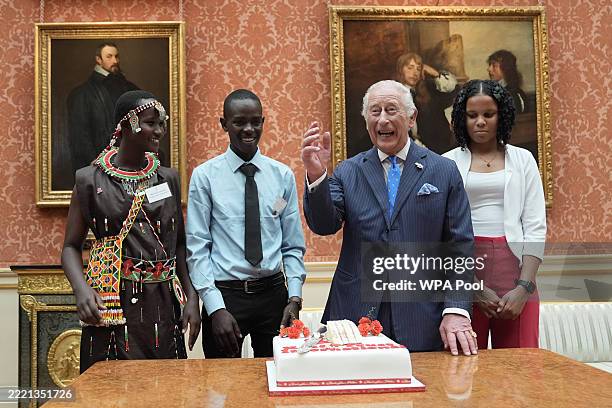 King Charles III cuts a cake to mark ten years of the Prince's Trust International, now known as the King's Trust International, as others look on...