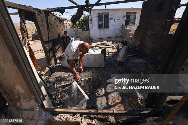 Palestinians Nasser Ishreiteh and his children clear burnt belongings in the living and kitchen area of their house after a reported attack overnight...