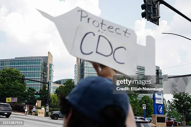 Protesters holds signs outside the CDC global headquarters during the first meeting of the CDC's Advisory Committee On Immunization Practices on June...