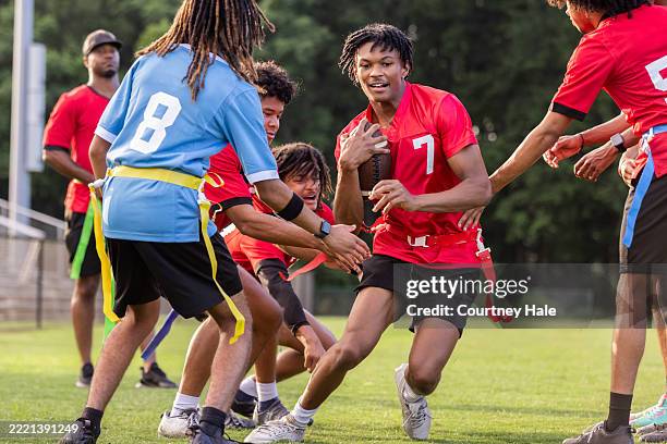 un athlète de l’école secondaire tient le ballon et court tout en jouant au flag-football avec son équipe sur un terrain de sport rural - championnat jeunes photos et images de collection