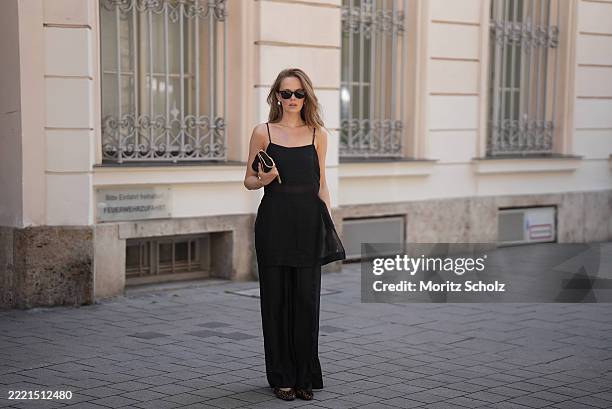 Pia Riegel is seen wearing a black long, sheer GZtrudi top with relaxed silhouette, spaghetti straps and straight neckline from Gestuz; a matching...