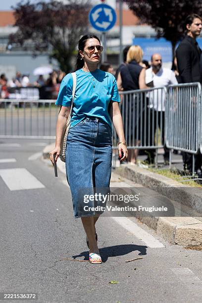 Guest wears a cobalt blue crew-neck T-shirt tucked into a high-waisted, medium-wash denim midi skirt with a front center seam, paired with...
