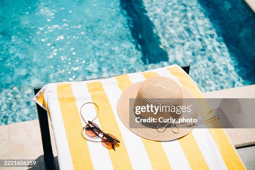 Sun lounger with towel and straw hat near the pool. Sun lounger with towel and straw hat near the pool.