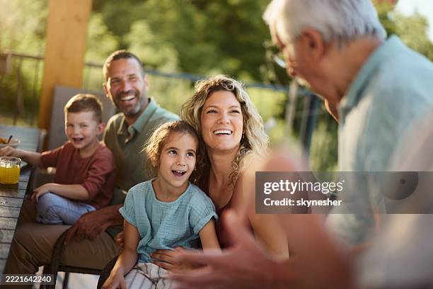 familia feliz hablando con el abuelo en una terraza. - familia multigeneracional fotografías e imágenes de stock
