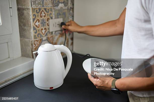 person plugging in electric kettle in home kitchen - kettle stock pictures, royalty-free photos & images