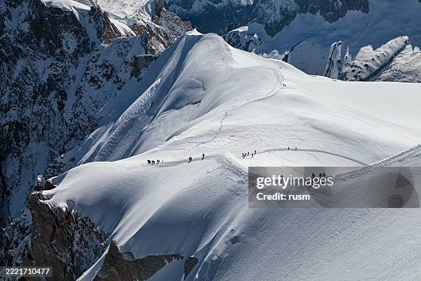 bergsteiger überqueren den verschneiten grat im mont-blanc-massiv, frankreich - aiguille du midi stock-fotos und bilder