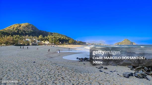people at beach against clear blue sky - praia stock pictures, royalty-free photos & images