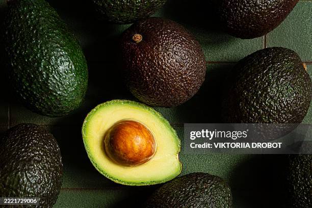 ripe avocados on a dark green background. - avocado stock pictures, royalty-free photos & images