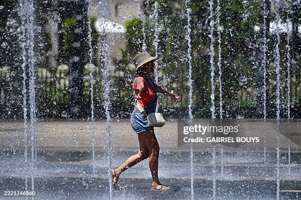 Woman walks through a fountain to cool off as a heatwave hits southern Europe, in Beziers, southern France, on June 28, 2025. Southern Europeans...