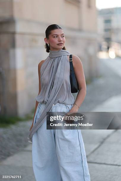 Sophia Geiss is seen wearing chunky silver hoop earrings, a silver nose ring, a semi-transparent grey chiffon sleeveless bodysuit with a halter neck...