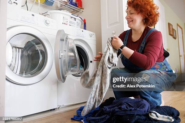 mid-adult redhead enjoys laundry routine at home. - droger stockfoto's en -beelden