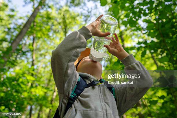 child drinking water from bottle outdoors in a forest setting - purified water stock pictures, royalty-free photos & images