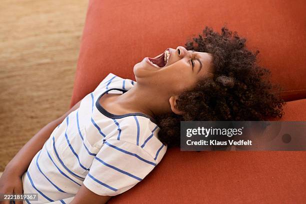 stubborn boy screaming while leaning on sofa - stubborn stock pictures, royalty-free photos & images